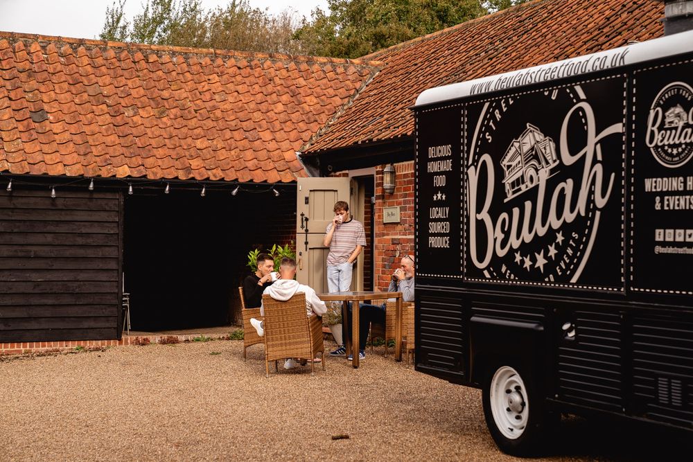 Black vintage Beulah wedding catering van parked outside a rustic barn wedding venue.