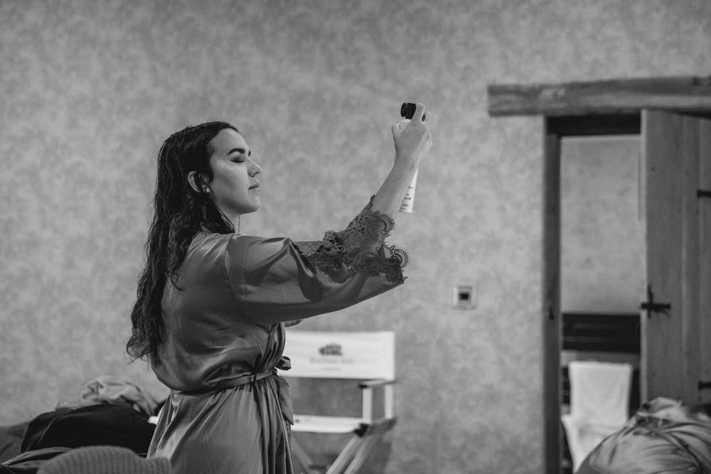 Bride in a silk robe taking a selfie in a black and white getting ready photo.
