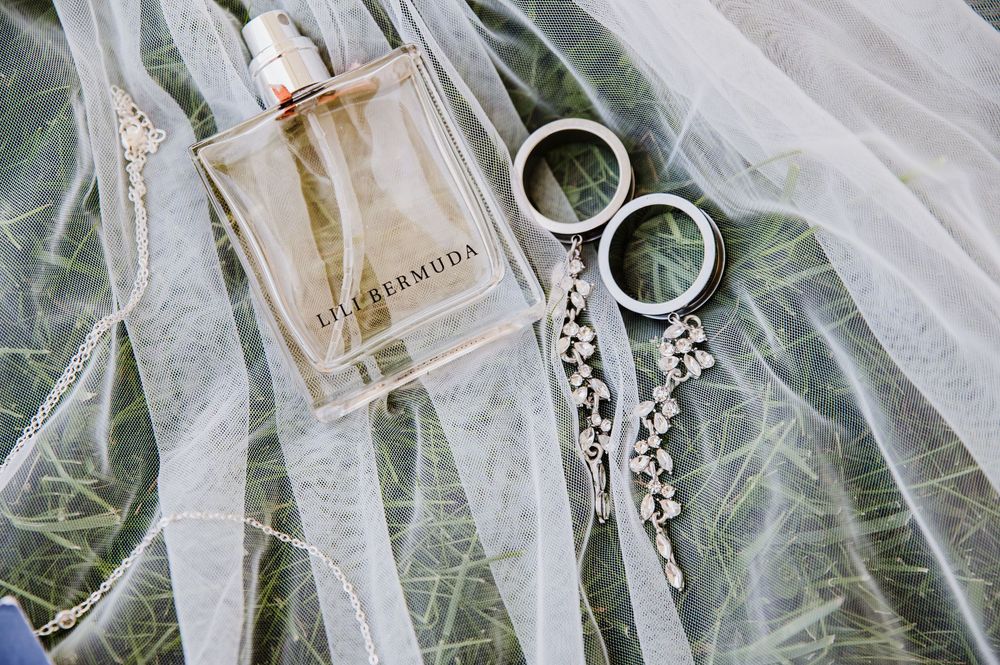 Lalique Bermuda perfume bottle with silver hoop earrings on a delicate white bridal veil.
