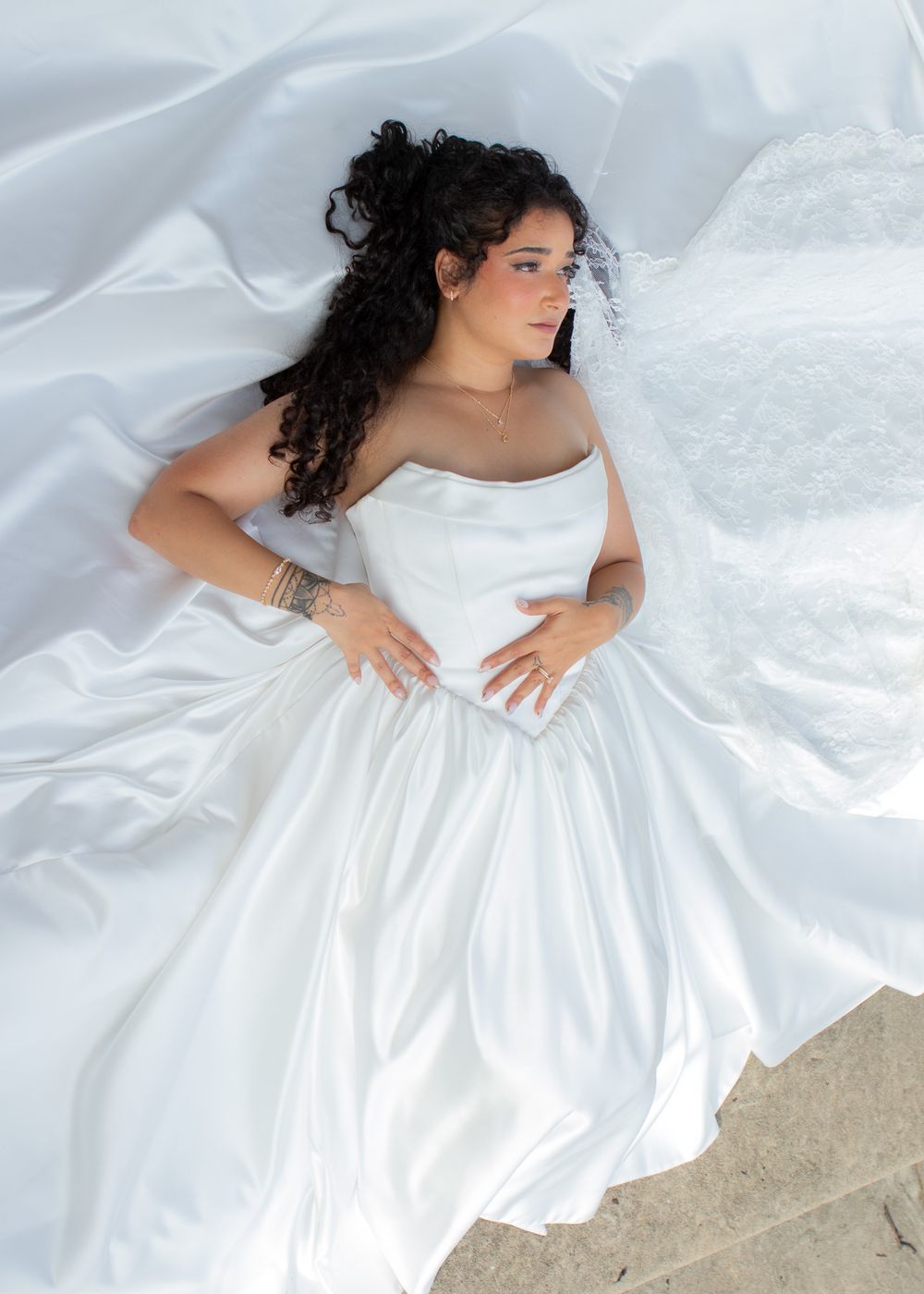 Gorgeous bride in a satin gown posing on the stairs of a Lakewood church before her wedding.