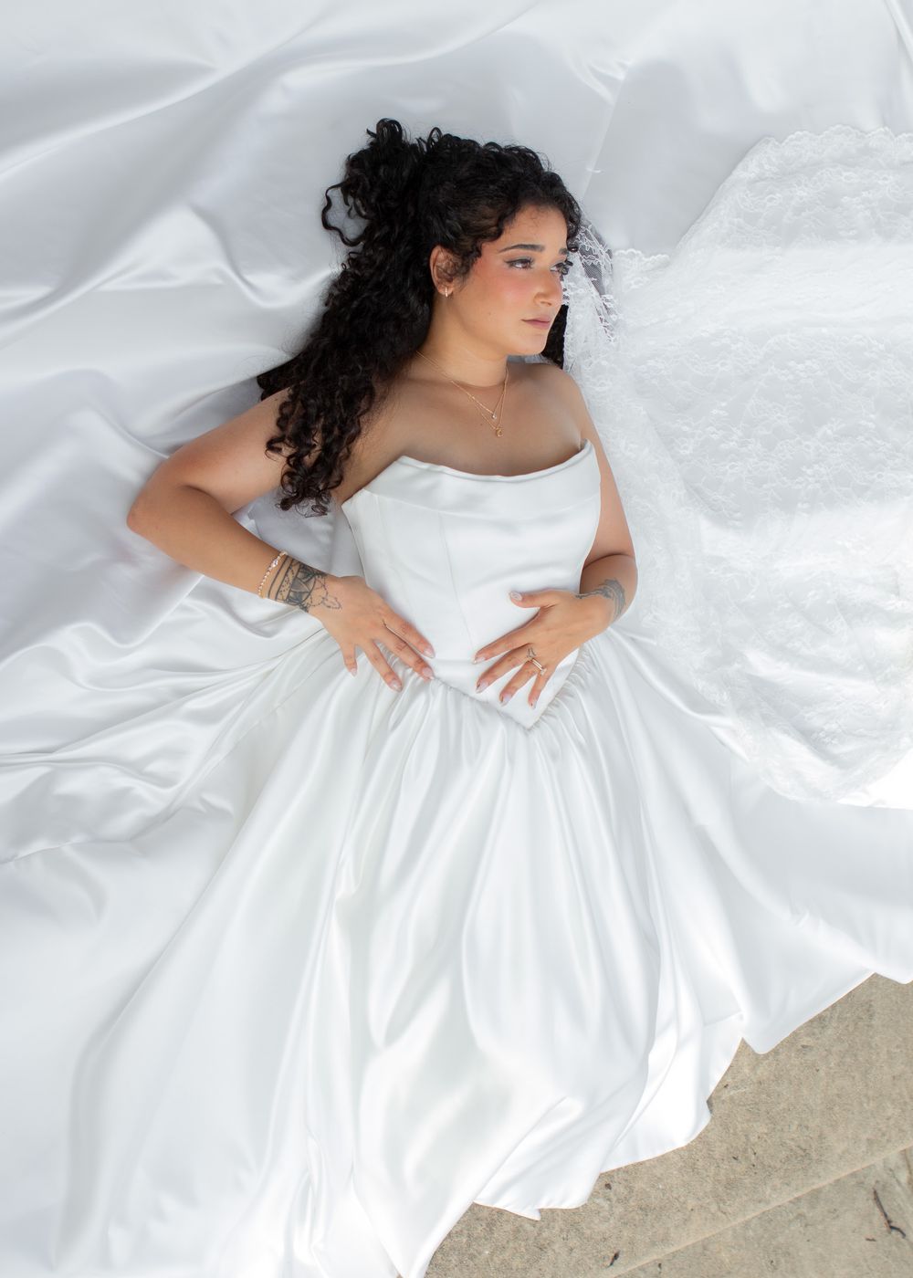 Gorgeous bride in a satin gown posing on the stairs of a Lakewood church before her wedding.