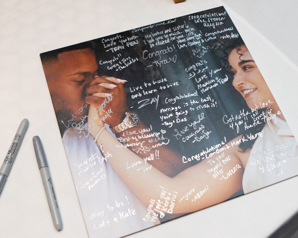 A wedding guest book photo print covered in congratulatory messages and signatures from wedding guests.
