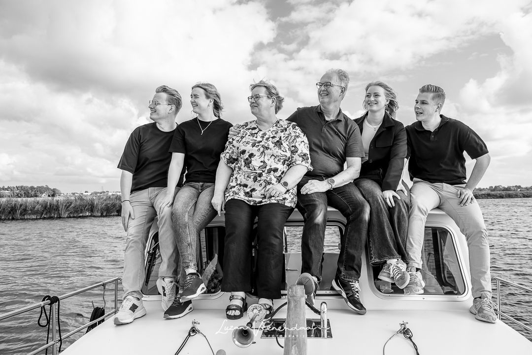 Zwart-witfoto van de hele familie samen op het dak van de boot tijdens de familiefotoshoot in Uitgeest"