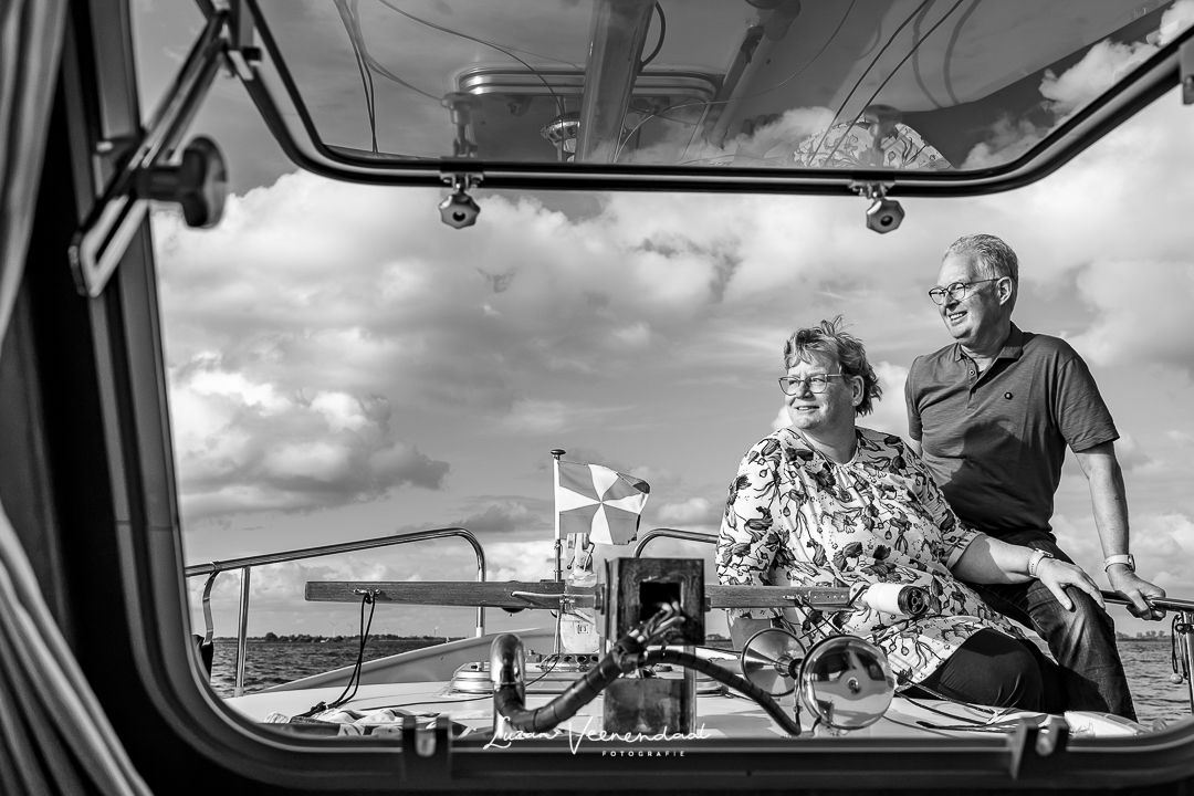 Zwart-witfoto van vader en moeder gefotografeerd door het raampje van de boot naar buiten tijdens de familiefotoshoot in Uitgeest