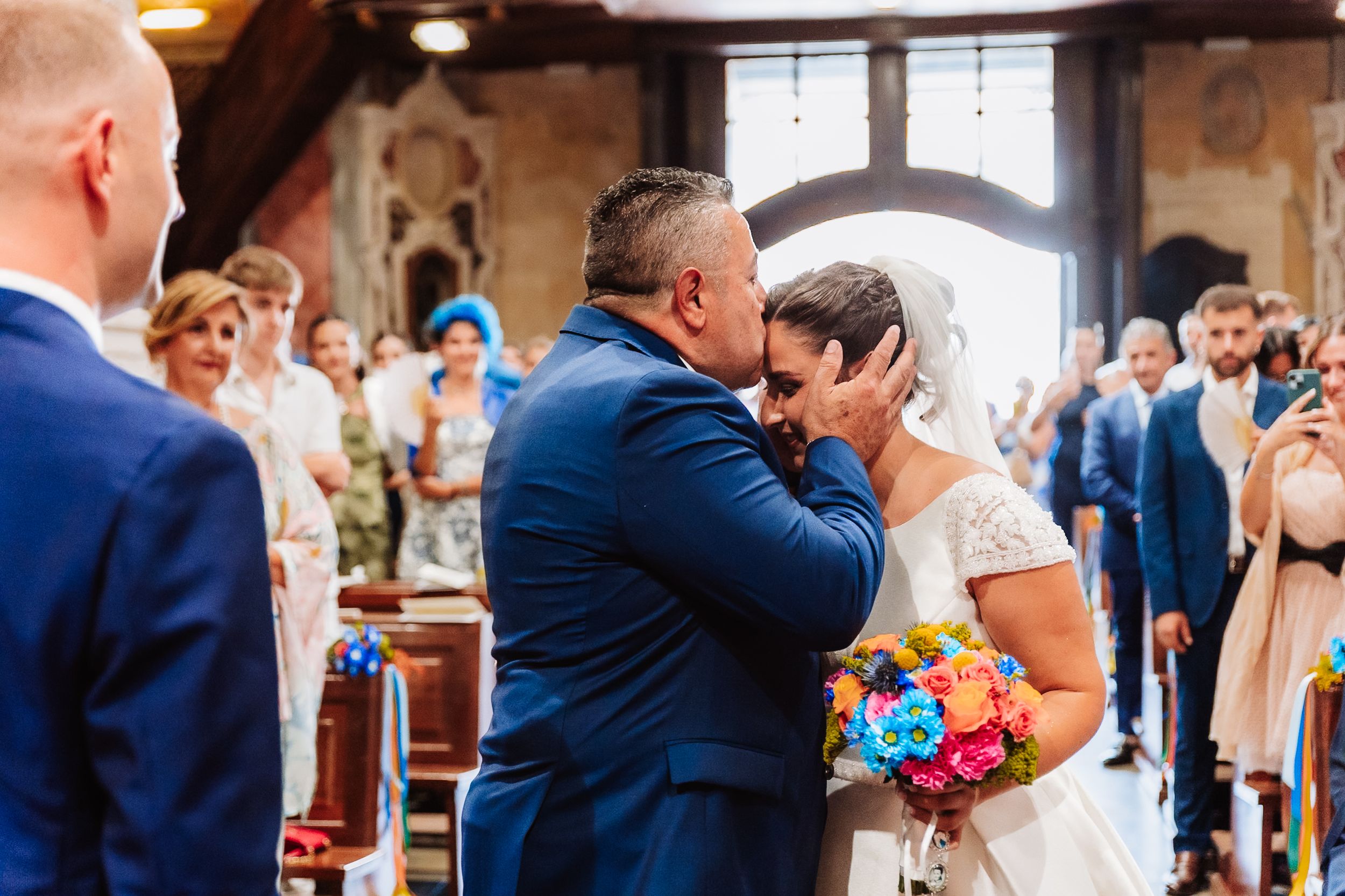 Emotional bride and groom sharing a tender moment at the altar during a colorful church wedding ceremony.