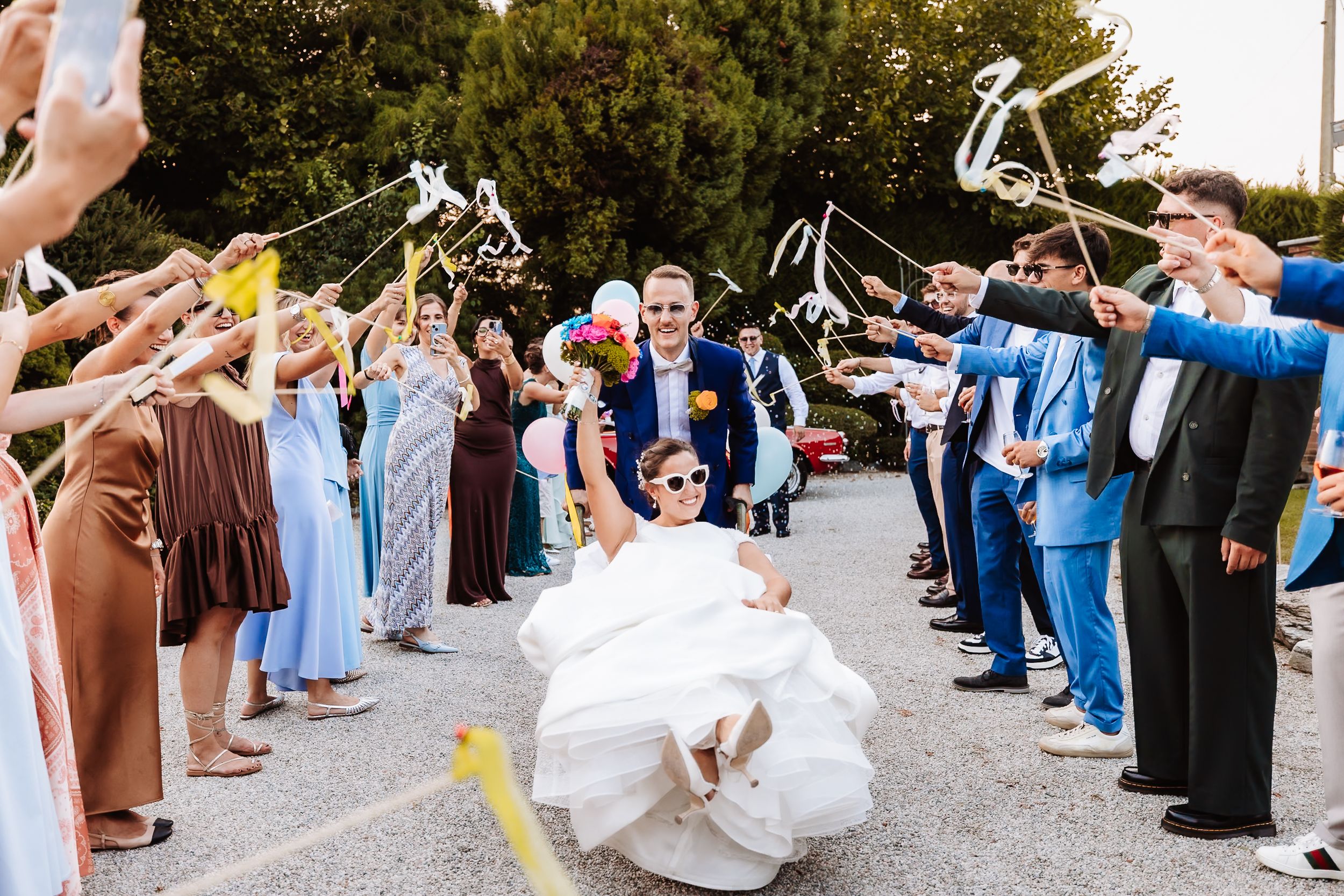 Bride and groom exit through bubble wand tunnel surrounded by cheering wedding guests.