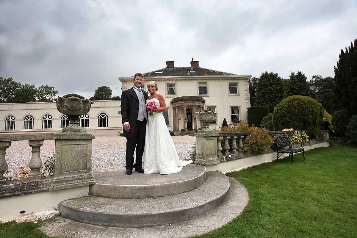 Bride and groom posing on stone steps outside Roundthorn Country House - Penrith
