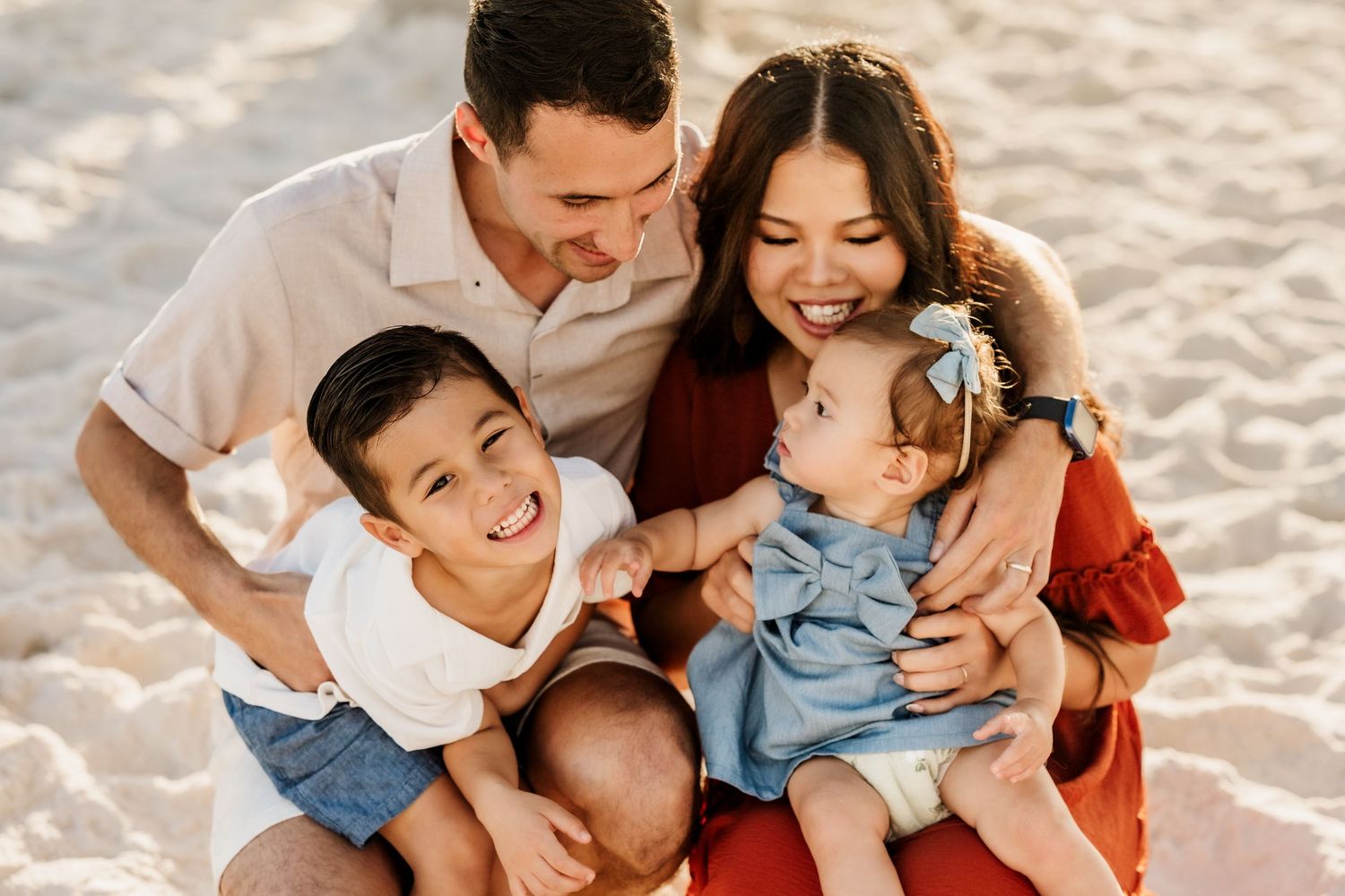 Family of four laughing together during a golden hour session on Pensacola Beach