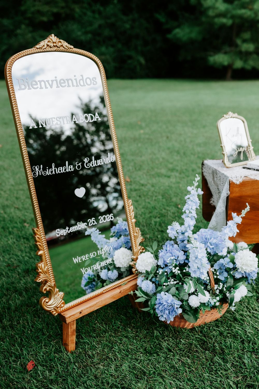 Gold ornate mirror wedding welcome sign reading Bienvenidos for Michaela & Eduardo, September 26 2025, with blue hydrangeas.