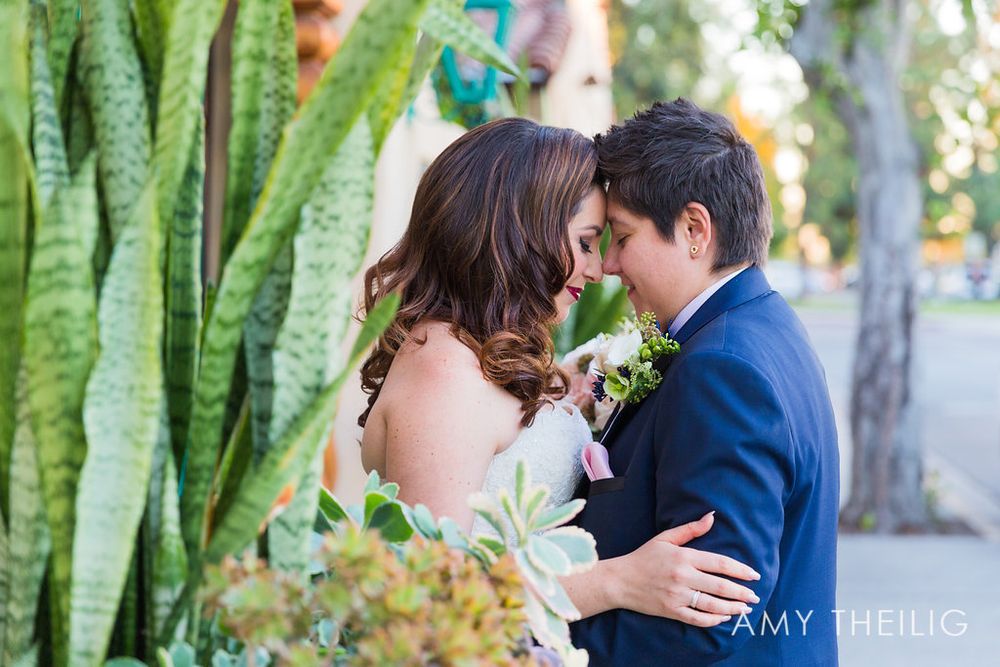 Bride and groom share an intimate moment surrounded by succulents and cacti at outdoor wedding venue.