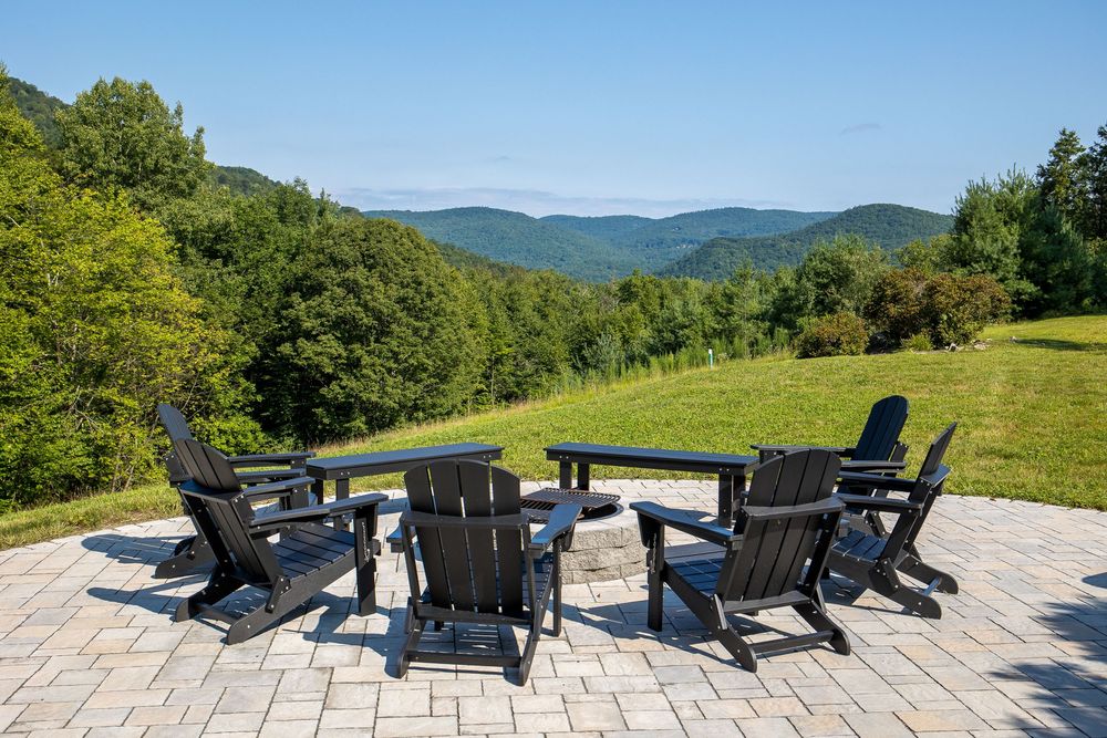 Black Adirondack chairs arranged on stone patio with breathtaking Green Mountain panoramic views.