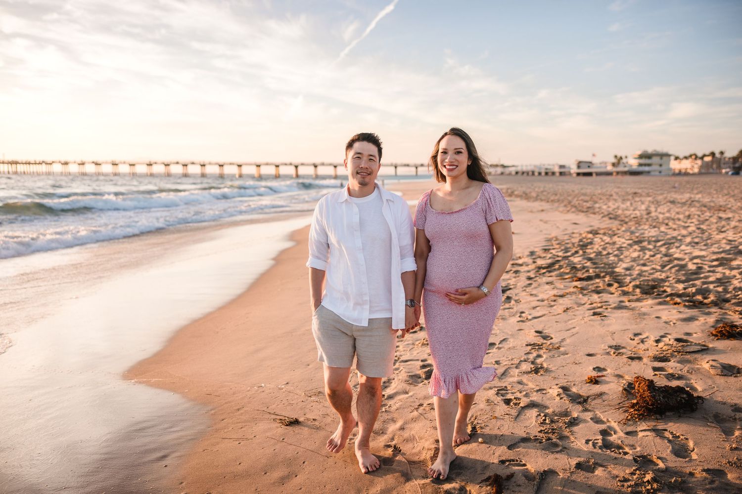Couple embracing while standing on a coastal cliff overlooking the ocean surrounded by golden wildflowers.