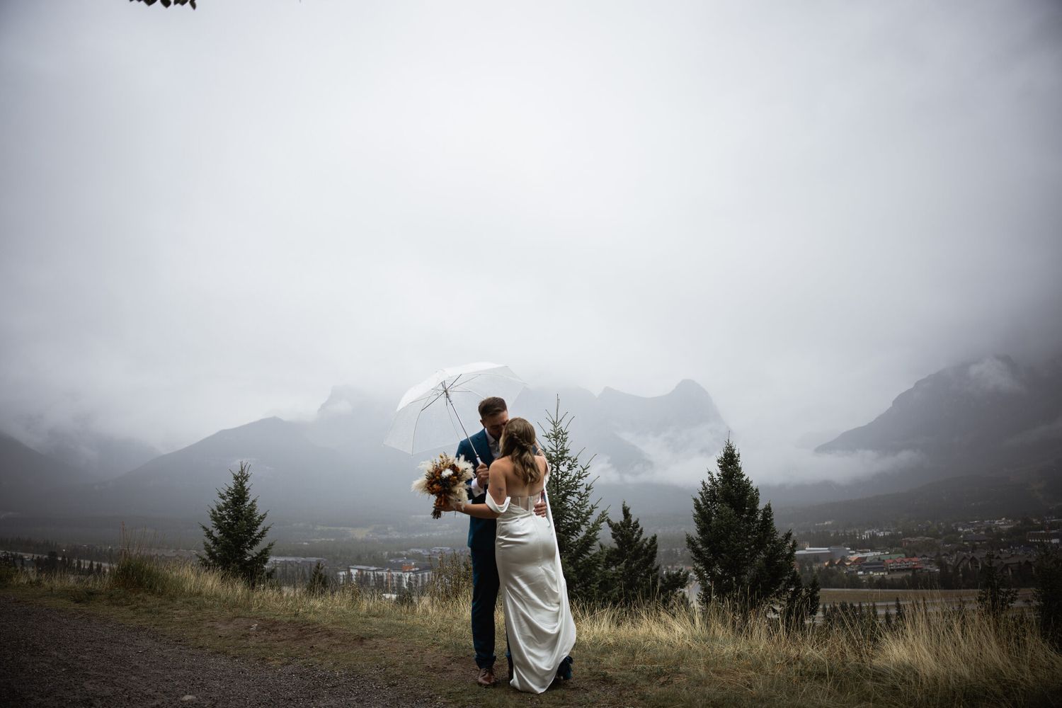 Bride and groom embrace on a misty overlook above Canmore, Rocky Mountain wedding photography