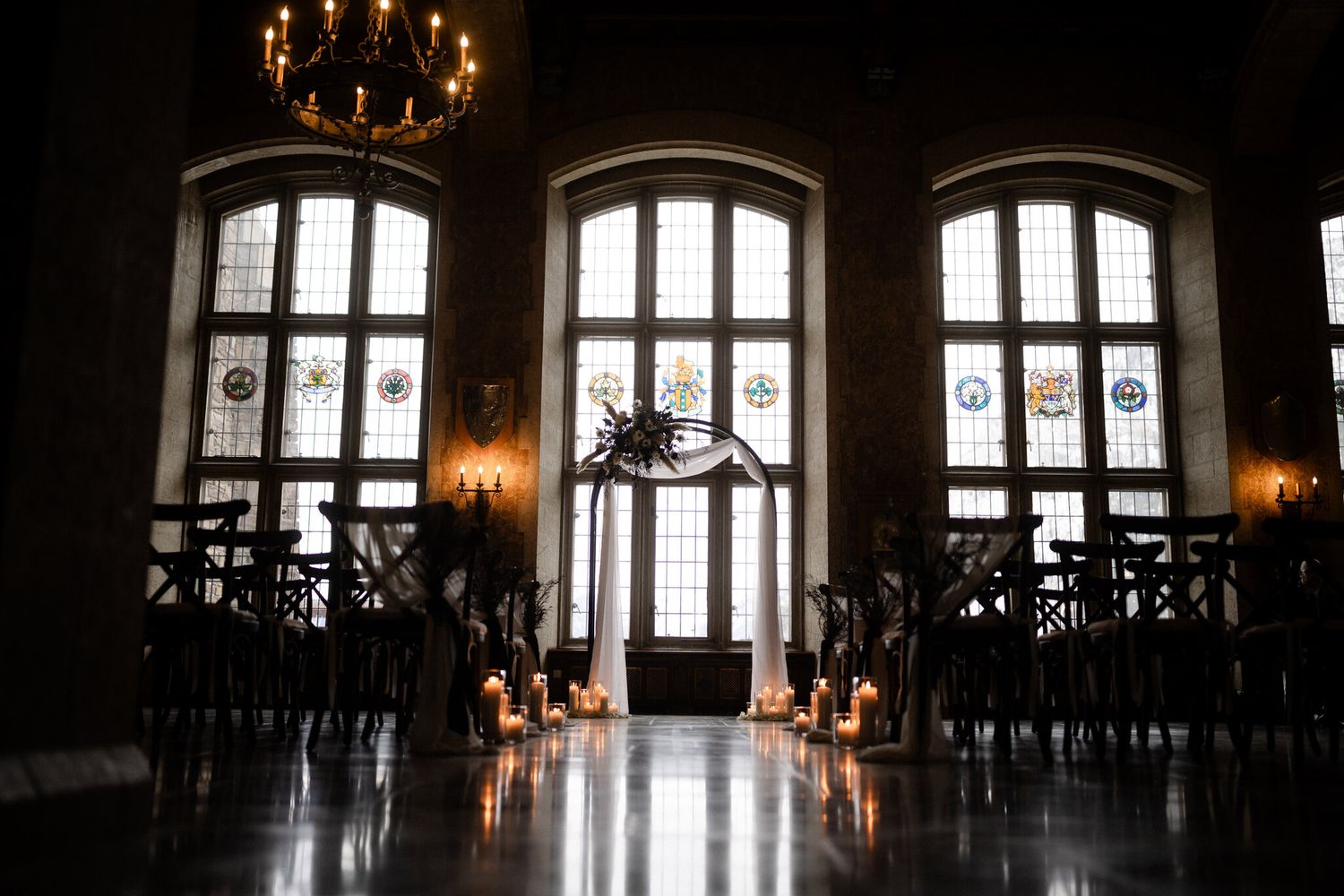 Moody candlelit ceremony space under stained glass and chandelier at a Fairmont Banff Springs Christmas wedding
