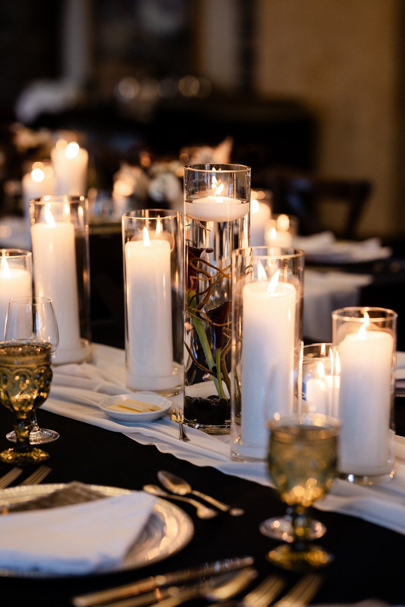 Floating candle centrepiece with pillar candles and gold goblets at a Banff Christmas wedding reception