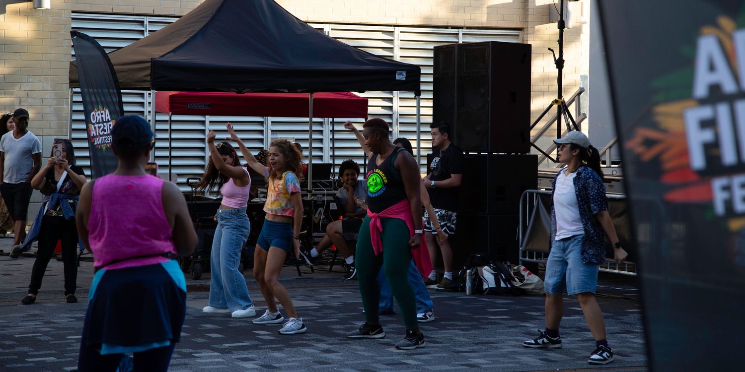 People dancing outdoors at a festival near a large speaker and black tent stage.