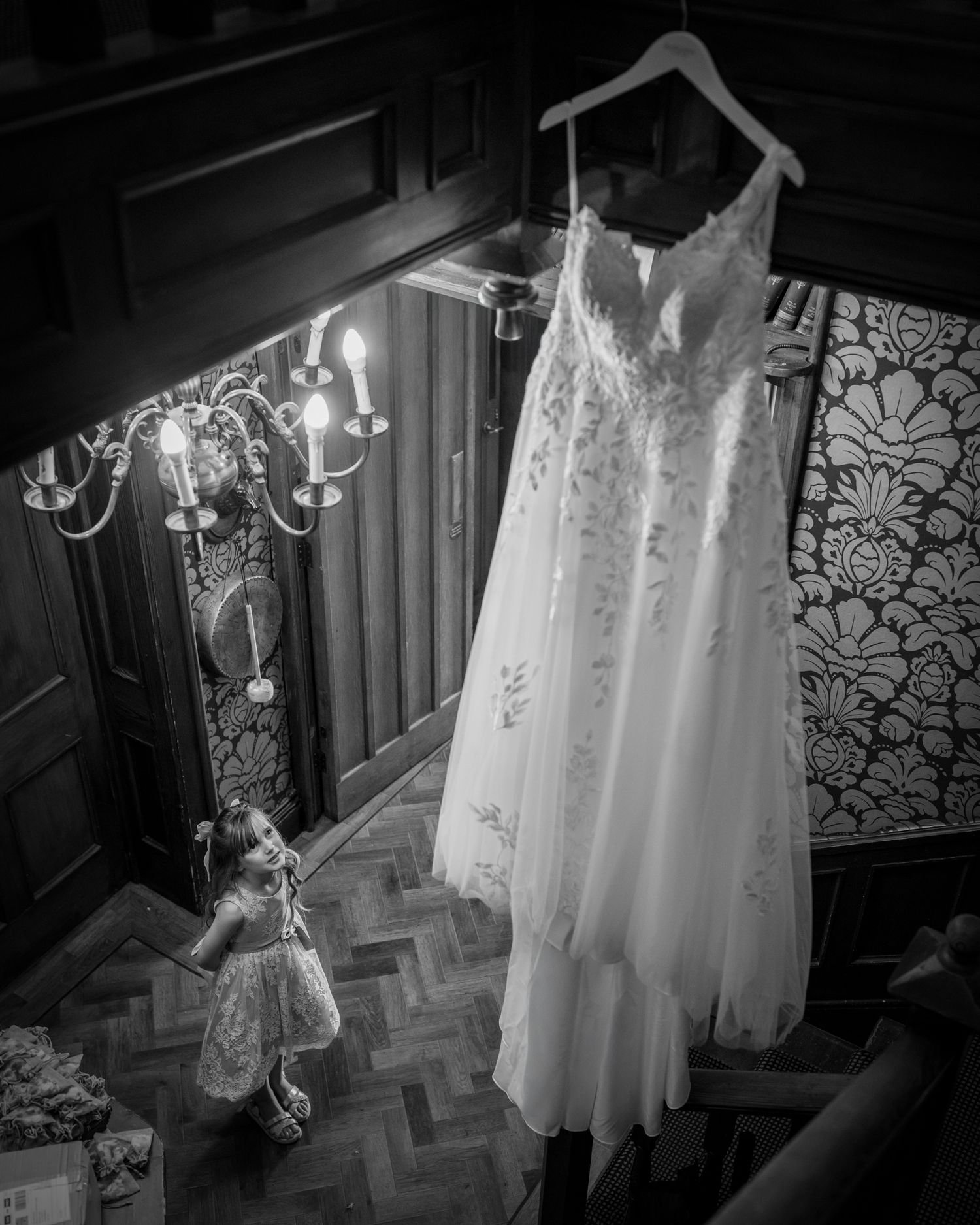 Young flower girl looking up at the bride's wedding dress inside Broadoaks Country House