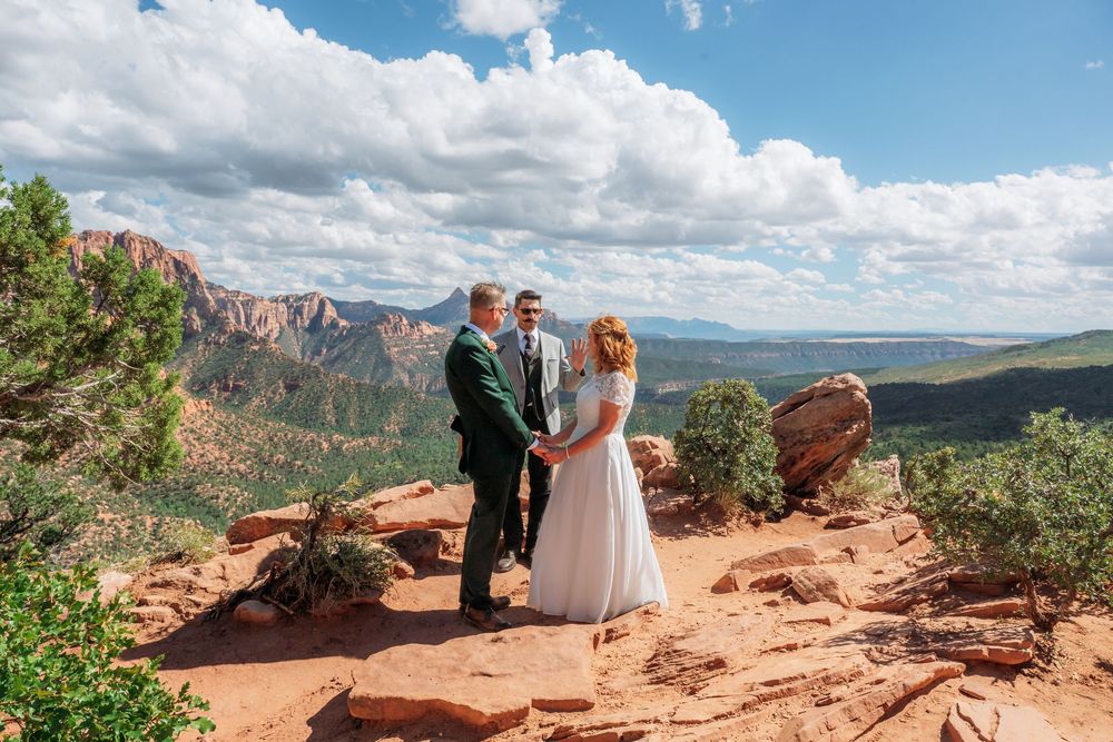 Bride and groom hold hands during outdoor elopement ceremony on red rock overlook in Sedona Arizona.
