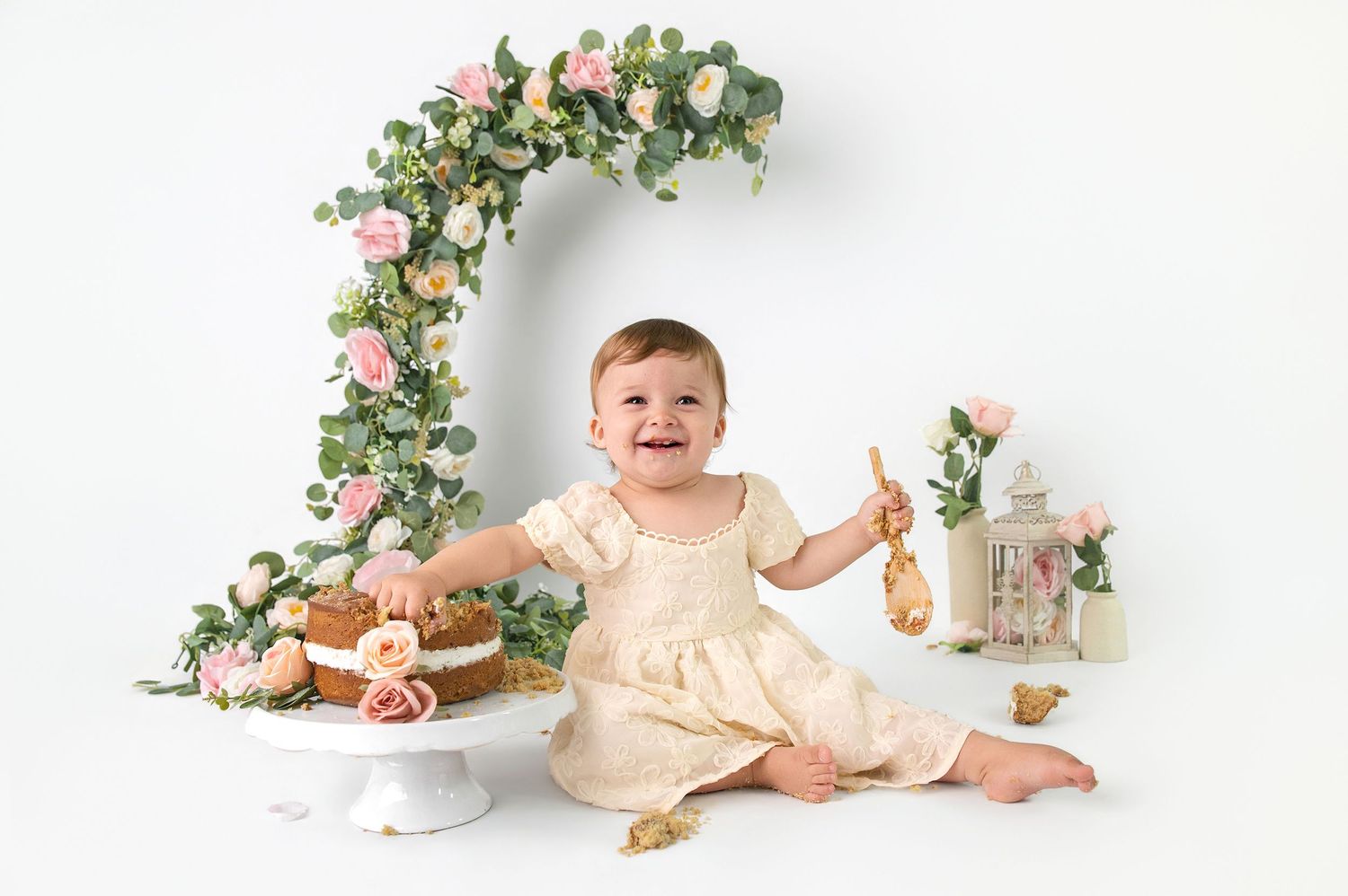 Smiling pregnant woman in sheer peach tulle robe posing against a soft yellow background, showcasing her baby bump.