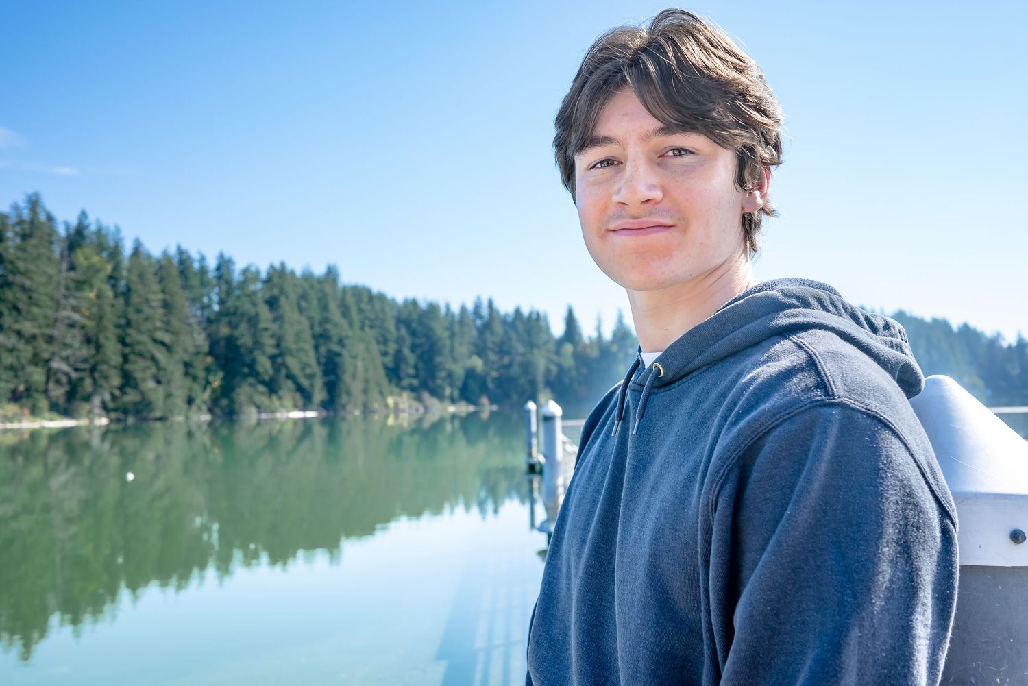 High school senior portrait with Lake Wilderness and the forested shoreline behind him