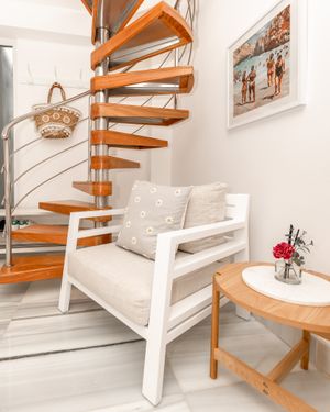 Spiral wooden staircase with white seating area and small round side table.