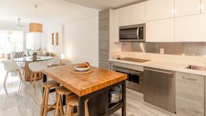 Modern kitchen with butcher block island, stainless appliances, and white cabinetry.