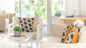 Bright coastal living room with white furniture and patterned throw pillows.