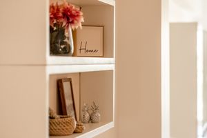 Decorative shelf display with 'Home' sign, vase of flowers, and rustic accessories.
