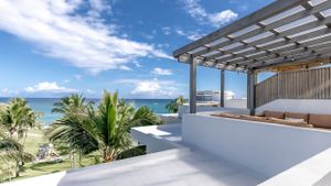 Luxurious oceanfront terrace with covered pergola and lounge seating overlooking tropical palm trees and turquoise waters.