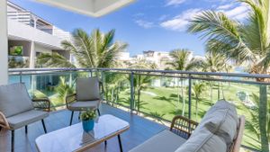 Luxury balcony with comfortable seating overlooking tropical resort grounds and palm trees.