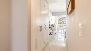 Bright white hallway with built-in storage and natural light streaming through window at end.