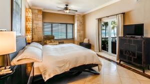 Modern beachfront bedroom with sliding glass doors and neutral decor.