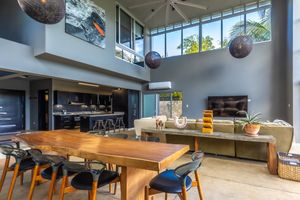 Spacious open floor plan combining dining area and living space with modern furnishings and dramatic ceiling height.