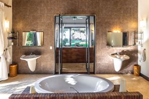 Elegant bathroom featuring oval soaking tub, dual vanities, and large window with scenic outdoor view.