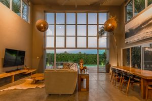 Spacious living room with floor-to-ceiling windows offering panoramic ocean views and modern furnishings.
