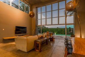 Modern living room with large windows, wooden furniture and palm tree views.