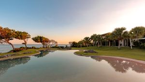 Scenic coastal property with infinity pool reflecting sunset sky.