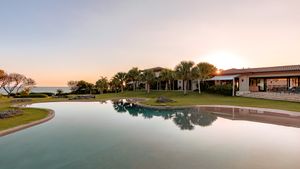 Luxurious waterfront property with reflecting pool at sunset.