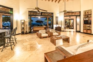Spacious living room with vaulted ceiling, exposed beams, and large windows overlooking ocean views.