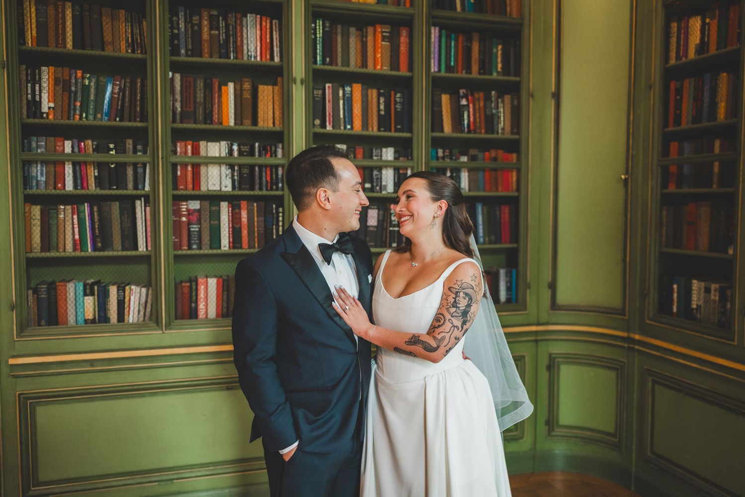 Bride and groom share a romantic moment in a library with green bookshelves at the Meridian house in washington dc