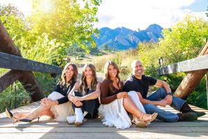 Group lounges together outdoors near mountains against a sunlit background as their photos are captured.