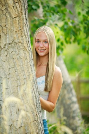 A casual outdoor portrait session among tree trunks and dappled sunlight in a natural wooded setting.
