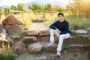 Person sitting casually on rocky steps with mountains in background.