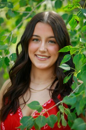A portrait series in a garden setting with green leaves and a red dress creating a vibrant natural backdrop.