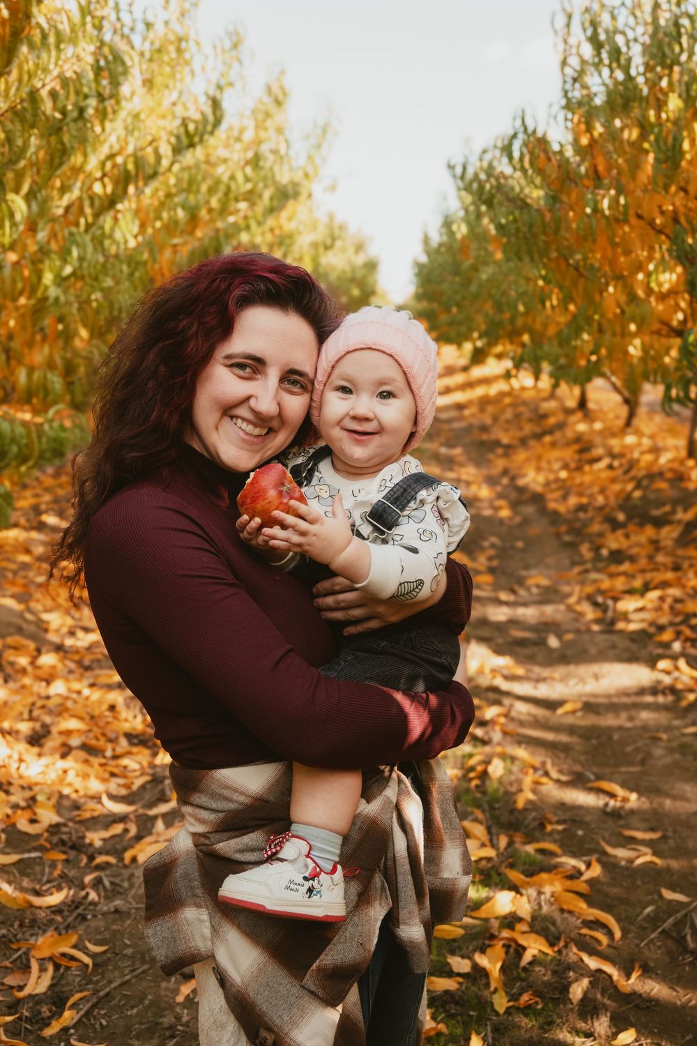 Fall family photoshoot in orchard with autumn colors and golden light.