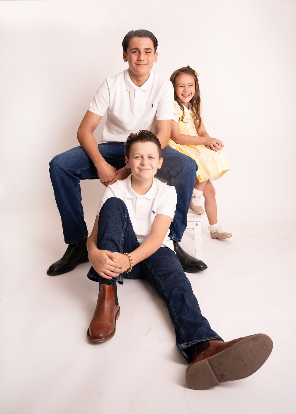 A family portrait in white and blue casual attire sitting together against a light background.