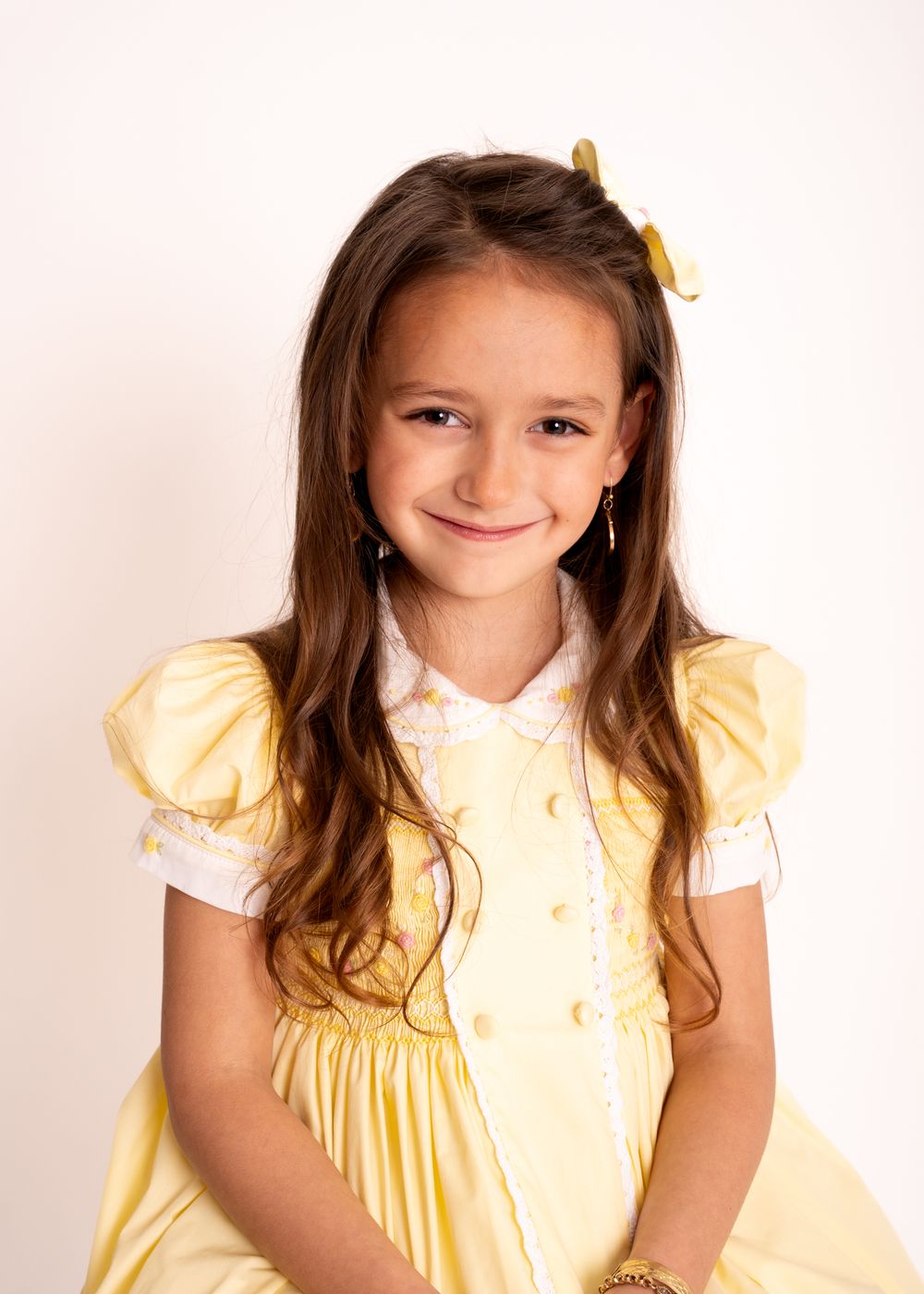 Young girl in yellow dress smiling and posing in multiple identical photos arranged side by side.