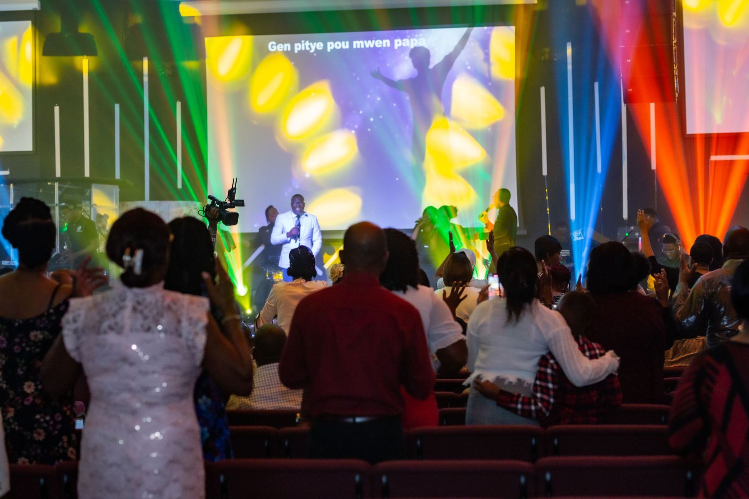 Vibrant concert scene with colorful lighting and crowd watching performers on stage.