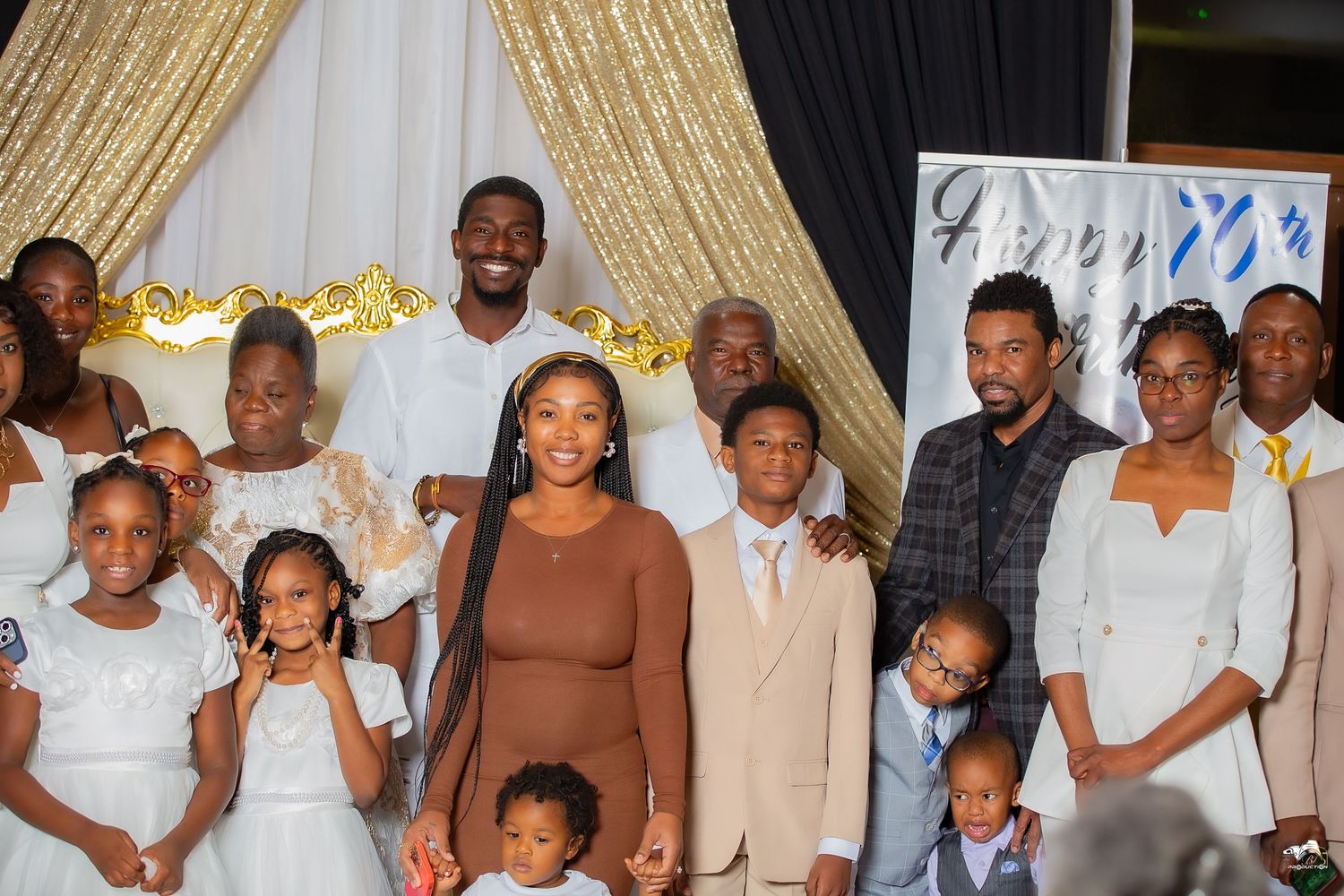 Family portrait with people dressed in white and neutral tones against gold backdrop.