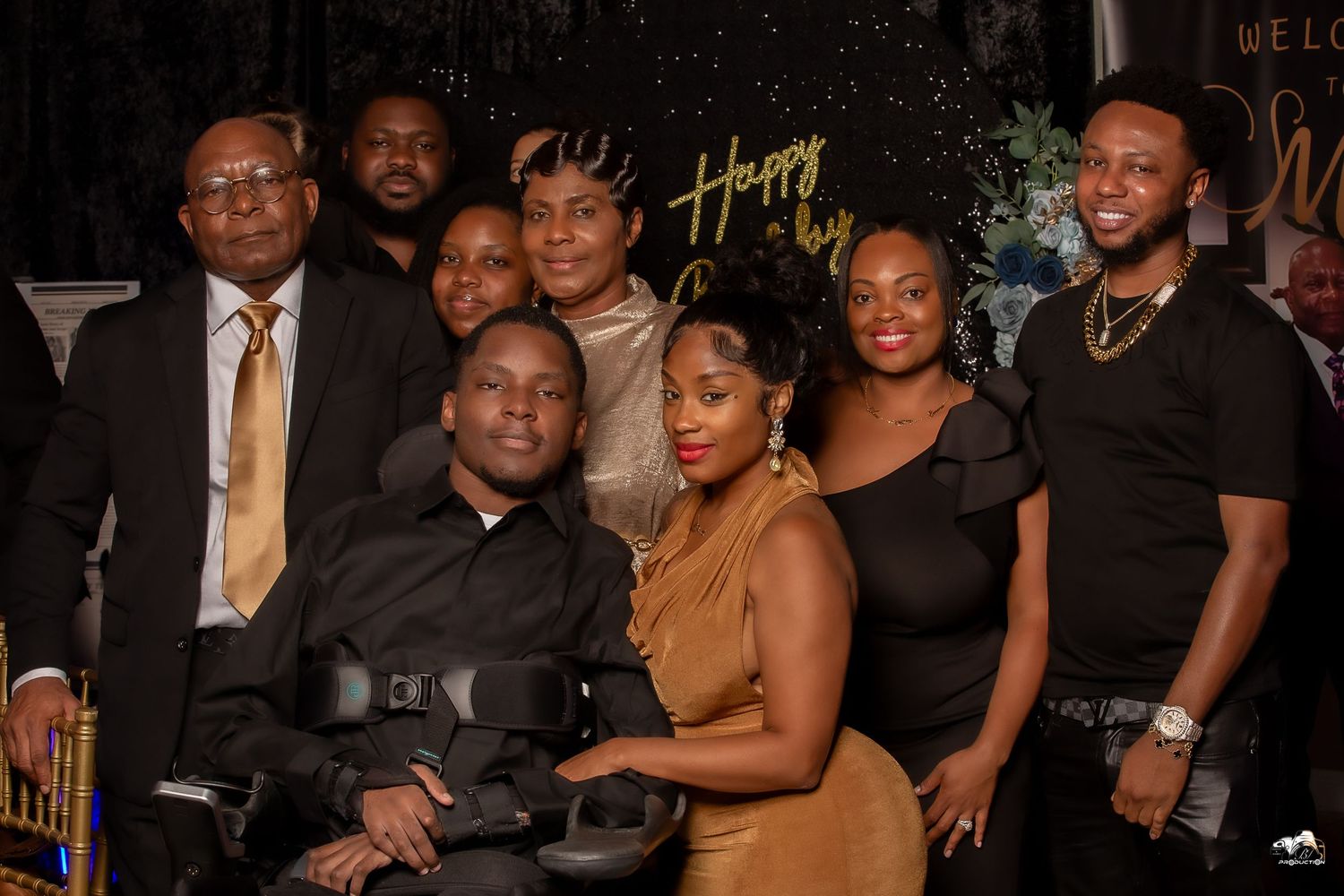 A festive group photo at an event with 'Happy' text visible in the background.